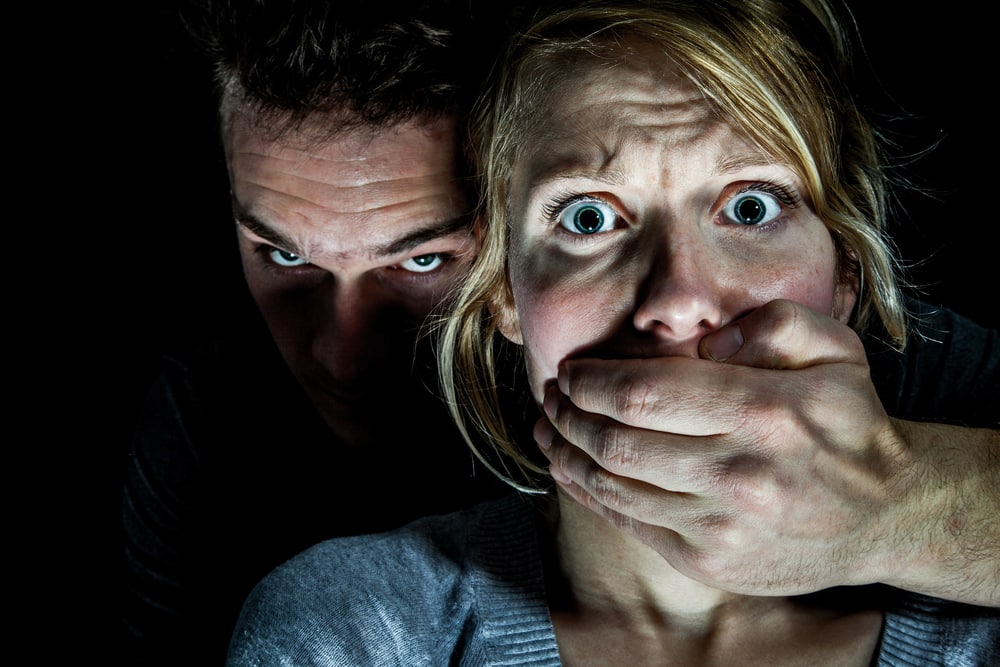 Man covering the mouth of woman during domestic abuse